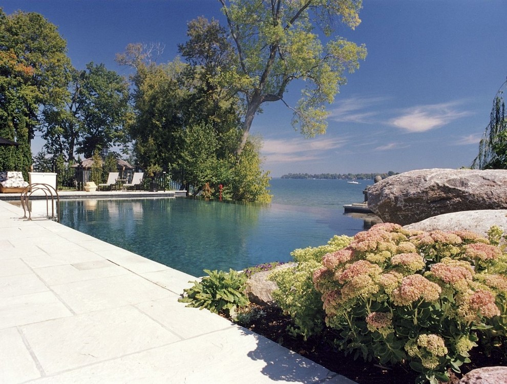 Идея дизайна: большой прямоугольный бассейн-инфинити на заднем дворе в современном стиле с покрытием из каменной брусчатки