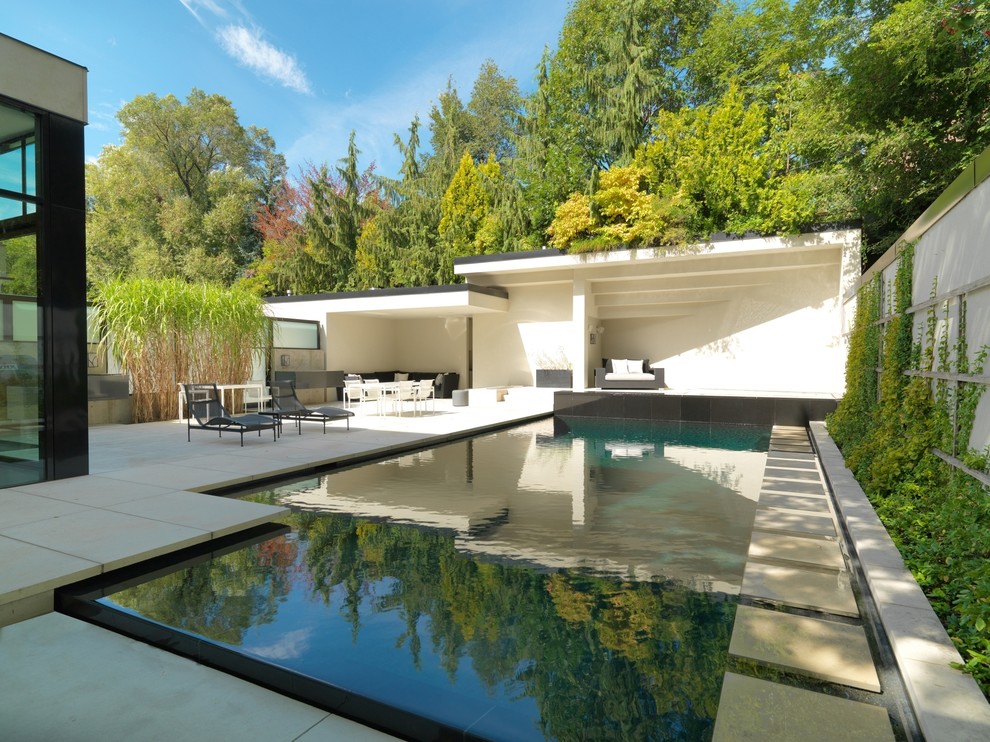 Ejemplo de casa de la piscina y piscina infinita contemporánea de tamaño medio rectangular en patio trasero con adoquines de piedra natural