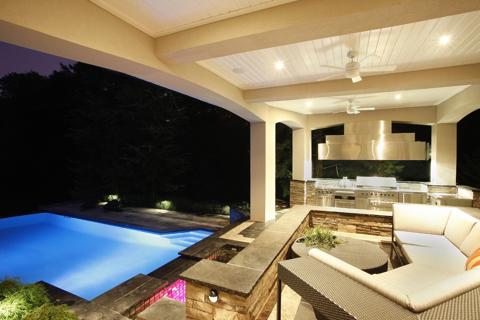 Immagine di una grande piscina a sfioro infinito contemporanea rettangolare dietro casa con una vasca idromassaggio e pavimentazioni in pietra naturale