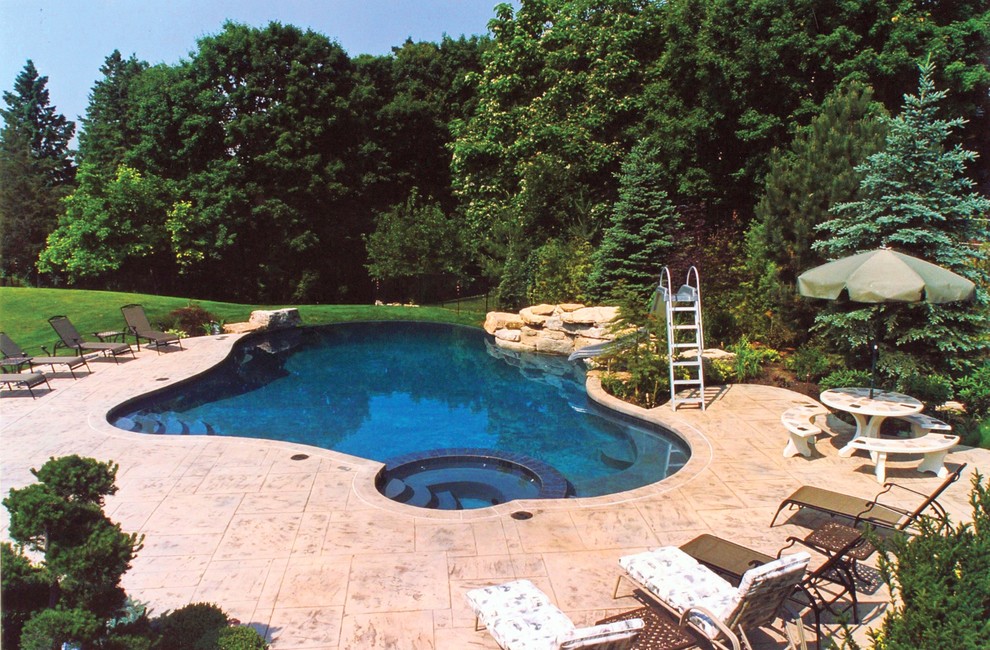 Réalisation d'une grande piscine à débordement et arrière design avec un bain bouillonnant et du béton estampé.