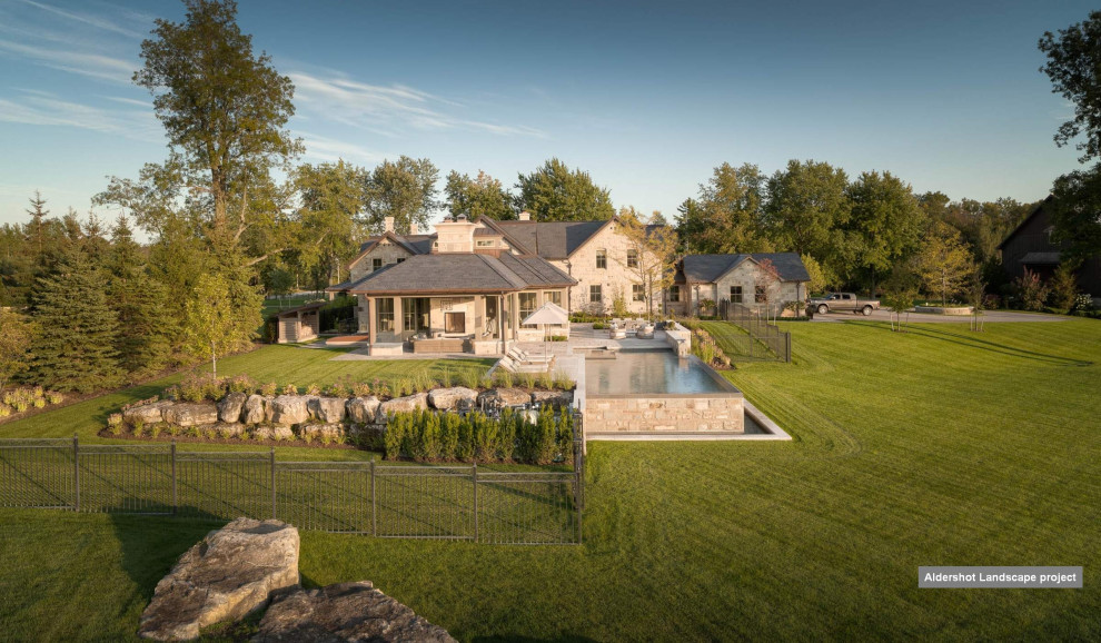 Mittelgroßer Klassischer Infinity-Pool hinter dem Haus in rechteckiger Form mit Pool-Gartenbau und Natursteinplatten in Toronto
