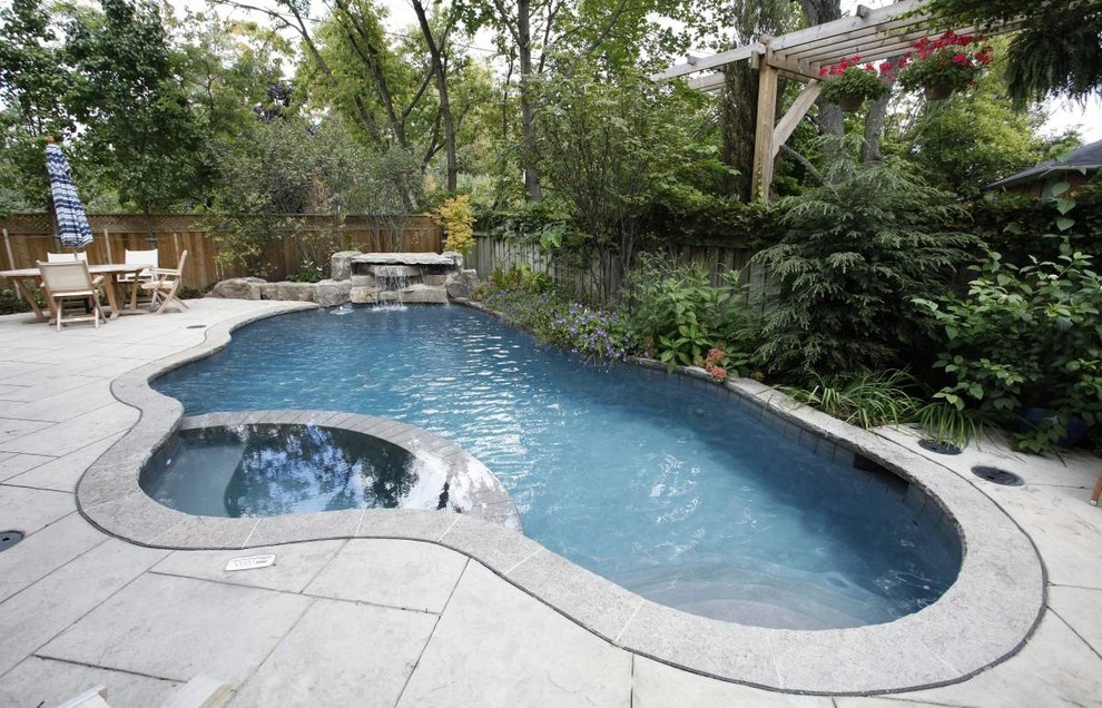 Foto de piscinas y jacuzzis alargados actuales pequeños a medida en patio trasero con adoquines de piedra natural