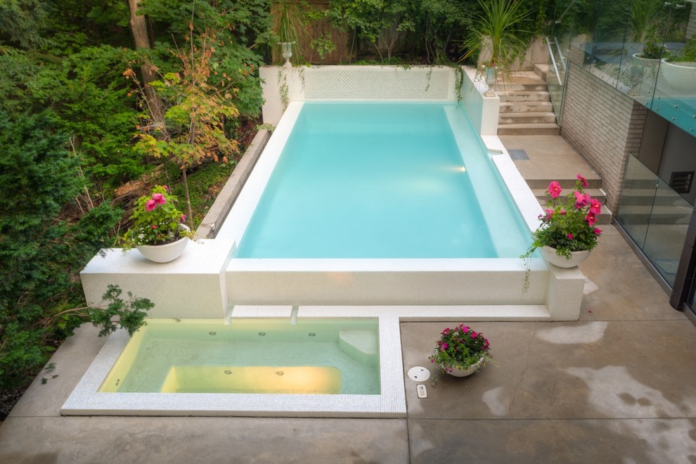 Ispirazione per una piccola piscina a sfioro infinito minimalista rettangolare dietro casa con una vasca idromassaggio e cemento stampato