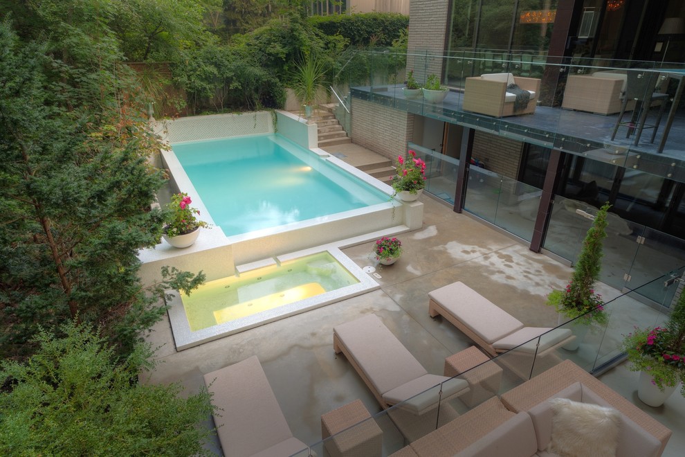 На фото: маленький прямоугольный бассейн-инфинити на заднем дворе в стиле модернизм с джакузи и покрытием из декоративного бетона для на участке и в саду с
