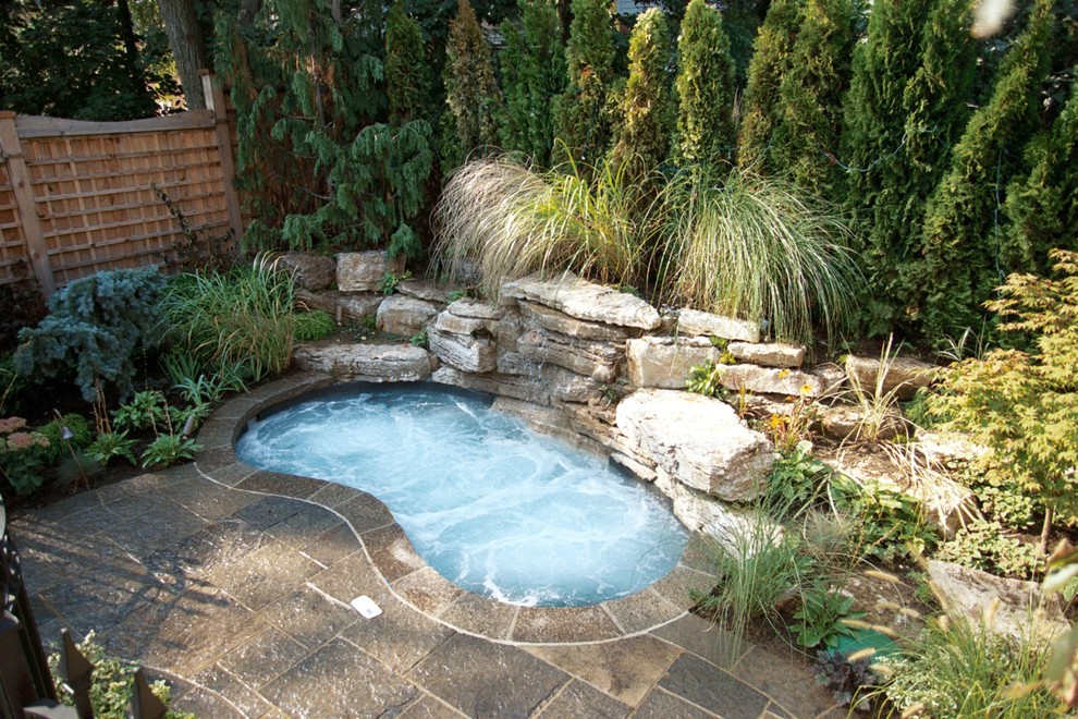 Exemple d'une petite piscine arrière tendance avec un bain bouillonnant et des pavés en pierre naturelle.