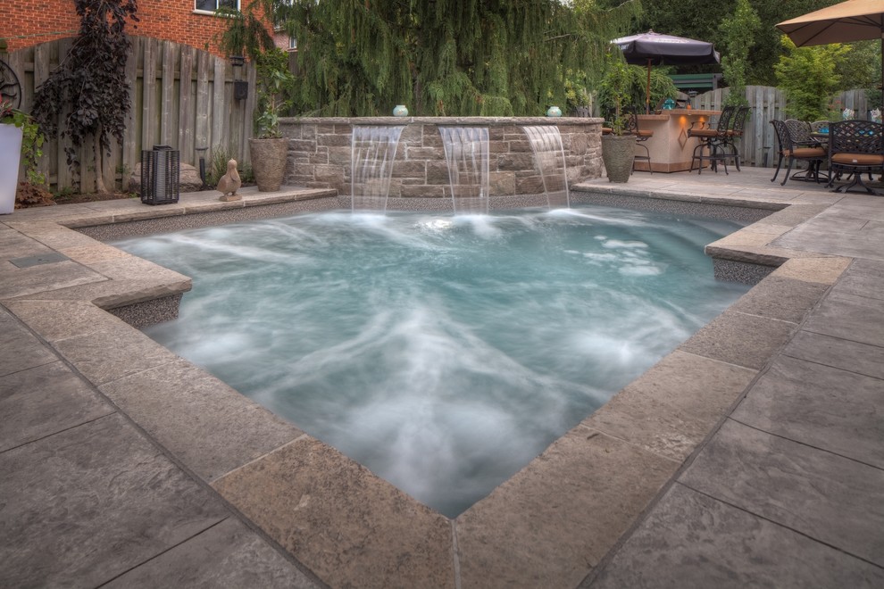Diseño de piscina con fuente actual pequeña a medida en patio trasero con suelo de hormigón estampado