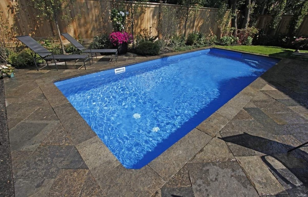 Réalisation d'une petite piscine arrière design rectangle avec des pavés en pierre naturelle.