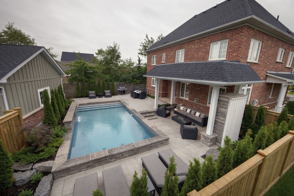 Photo of a small contemporary back custom shaped swimming pool in Toronto with a water feature and stamped concrete.