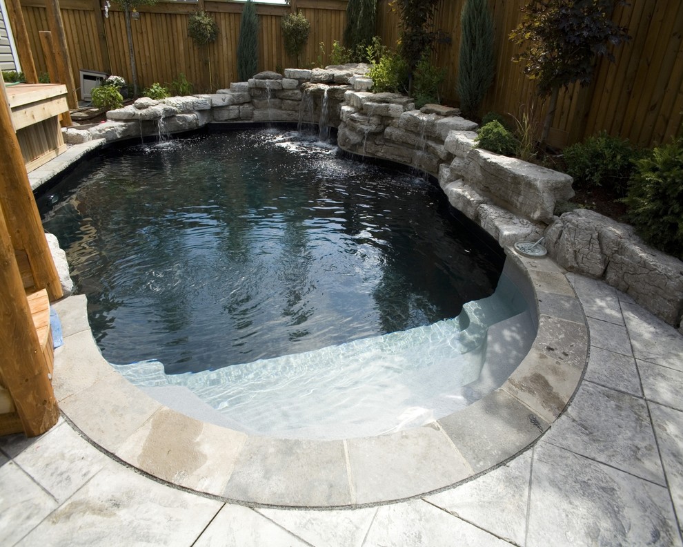 Design ideas for a small contemporary back custom shaped swimming pool in Toronto with a water feature and stamped concrete.