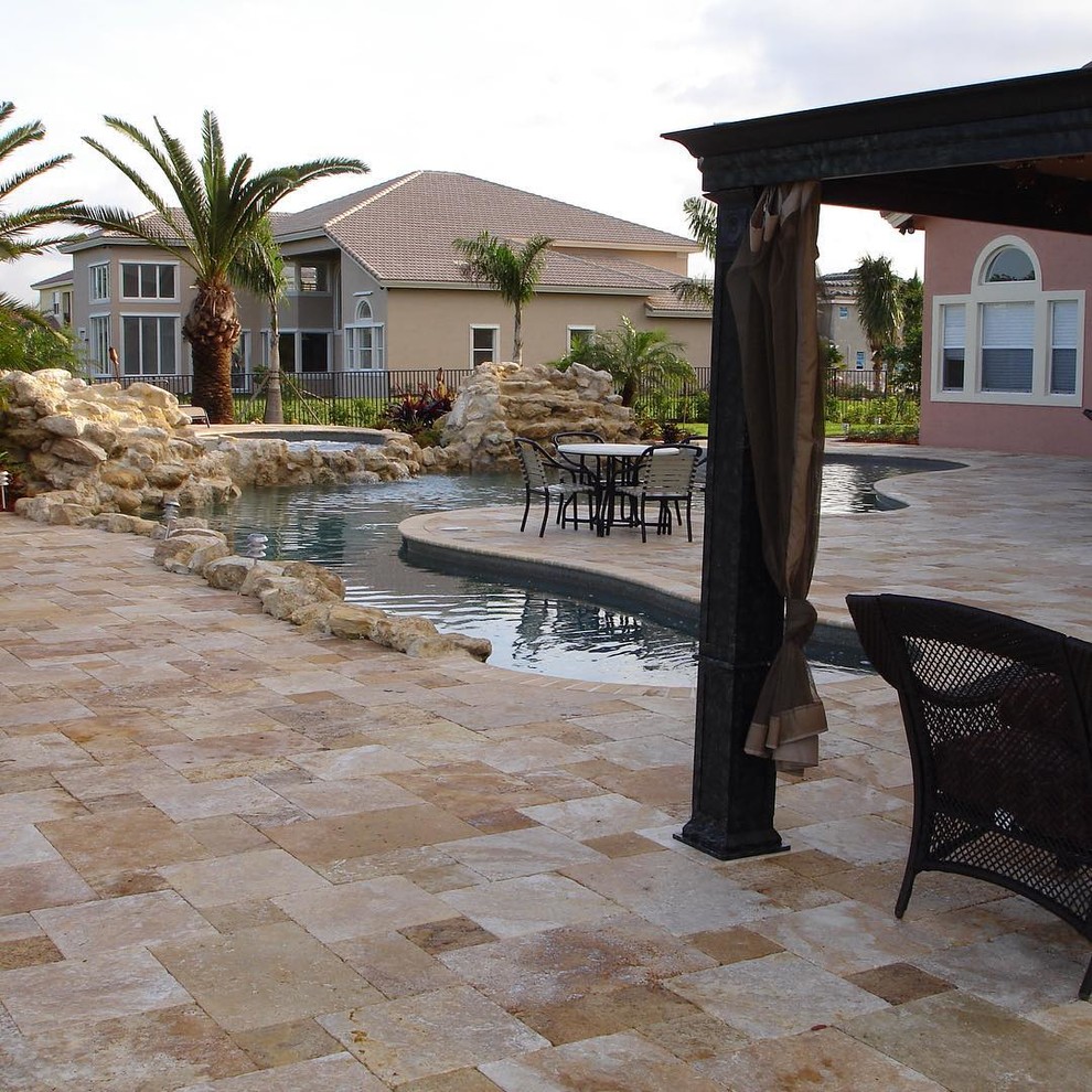 Immagine di una grande piscina naturale classica personalizzata dietro casa con una vasca idromassaggio e pavimentazioni in pietra naturale