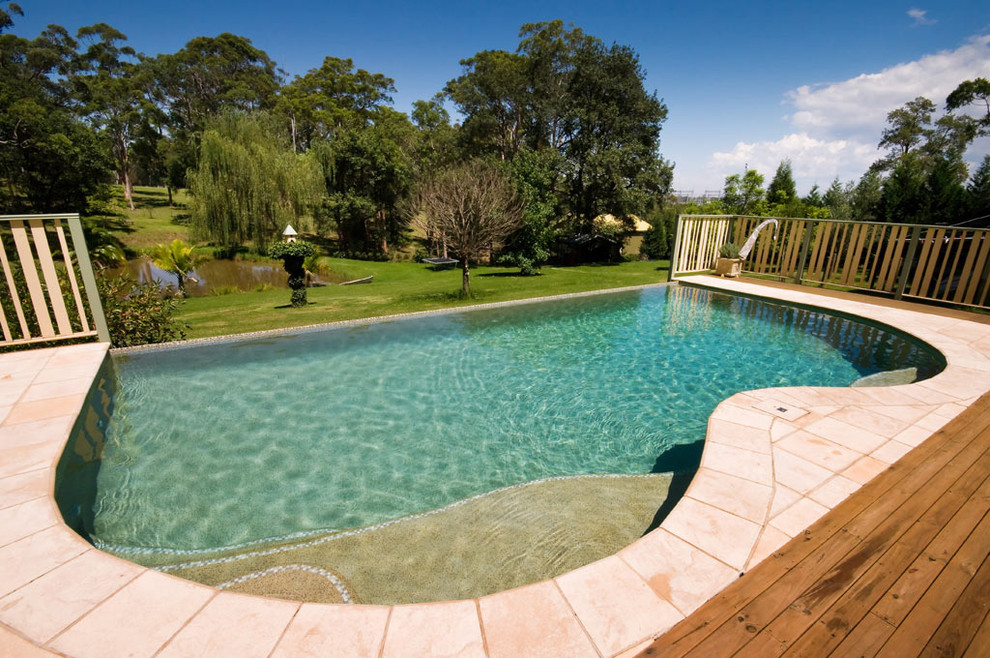 Medium sized modern back custom shaped above ground swimming pool in Sydney with concrete paving.