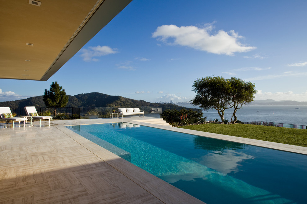 Imagen de piscina alargada moderna grande rectangular en patio trasero con suelo de baldosas