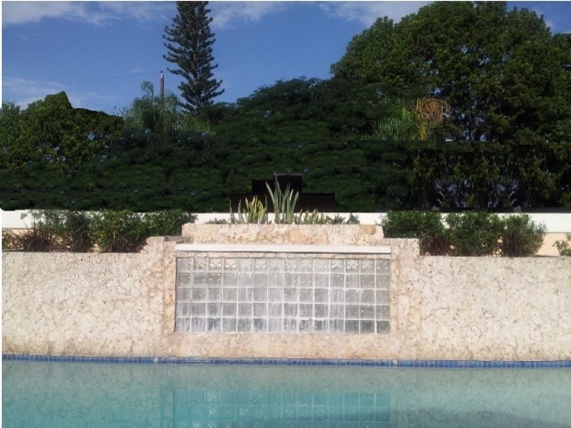 Foto di una piccola piscina fuori terra tropicale rettangolare dietro casa con una dépendance a bordo piscina e pavimentazioni in pietra naturale