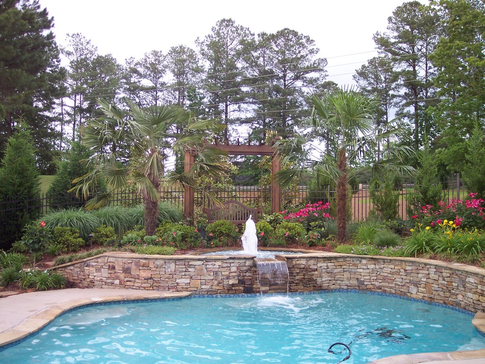 Inspiration for a mid-sized tropical backyard stamped concrete and custom-shaped hot tub remodel in Atlanta
