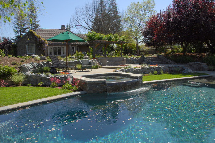 Esempio di una piscina monocorsia minimal rettangolare di medie dimensioni e dietro casa con una vasca idromassaggio e pavimentazioni in pietra naturale