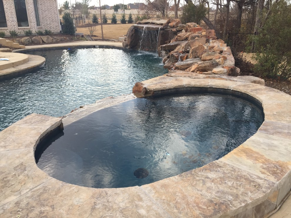 Design ideas for a large contemporary back kidney-shaped natural swimming pool in Dallas with a water feature and concrete slabs.