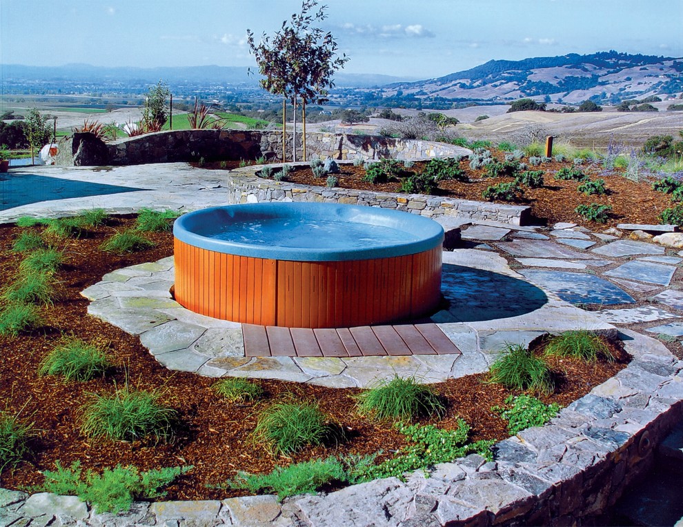 Foto di una piscina fuori terra mediterranea rotonda dietro casa con una vasca idromassaggio e pavimentazioni in pietra naturale