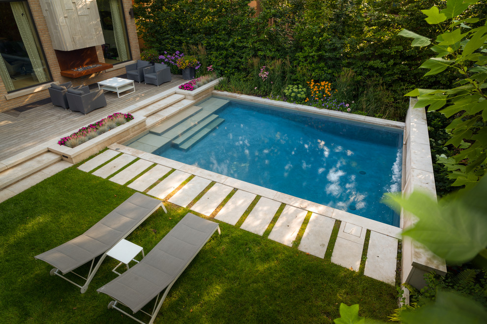 Réalisation d'une petite piscine arrière design rectangle avec un point d'eau et des pavés en pierre naturelle.