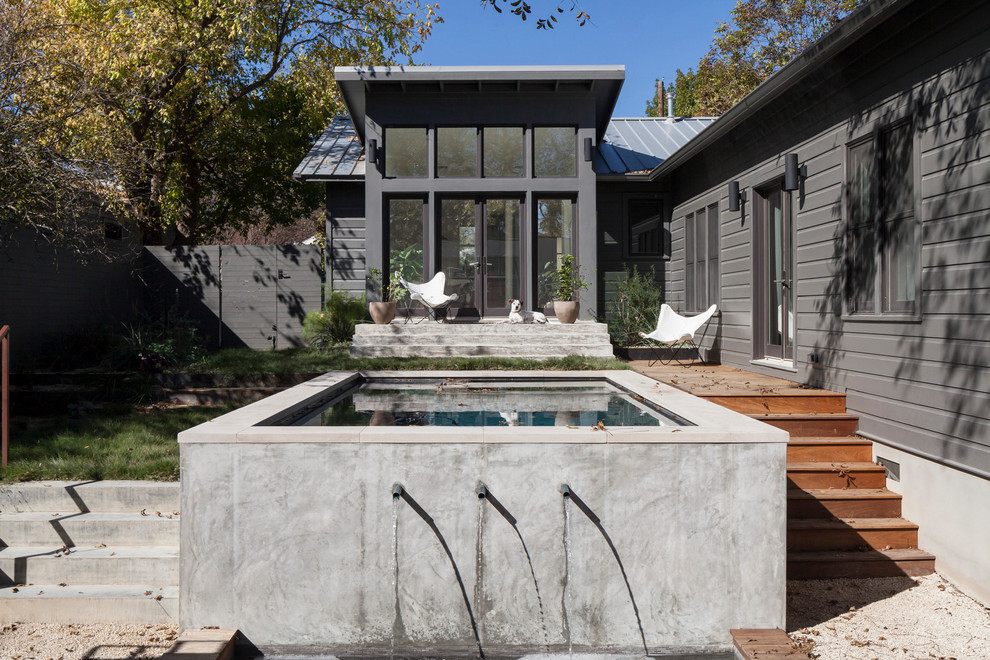 Imagen de piscina con fuente minimalista de tamaño medio rectangular en patio trasero con losas de hormigón