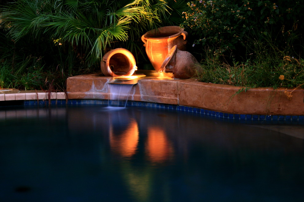 Imagen de piscina con fuente mediterránea en patio trasero