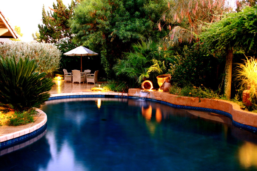 Modelo de piscina con fuente mediterránea en patio trasero con suelo de baldosas