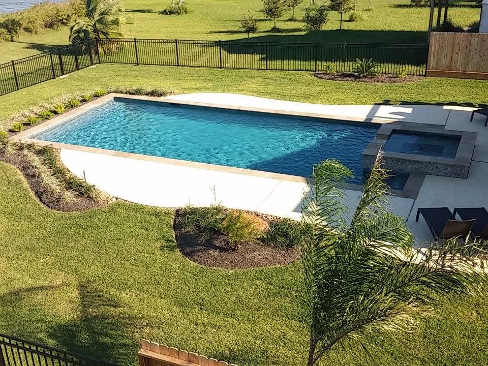 Idee per una grande piscina monocorsia tradizionale rettangolare dietro casa con una vasca idromassaggio e lastre di cemento