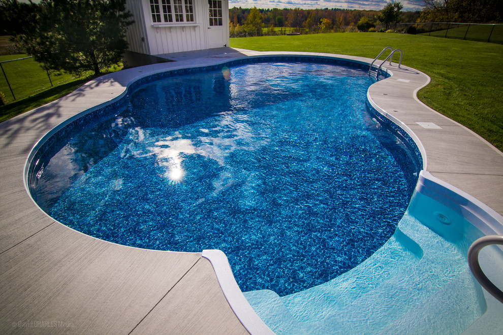Exemple d'une grande piscine arrière chic avec un bain bouillonnant et une dalle de béton.