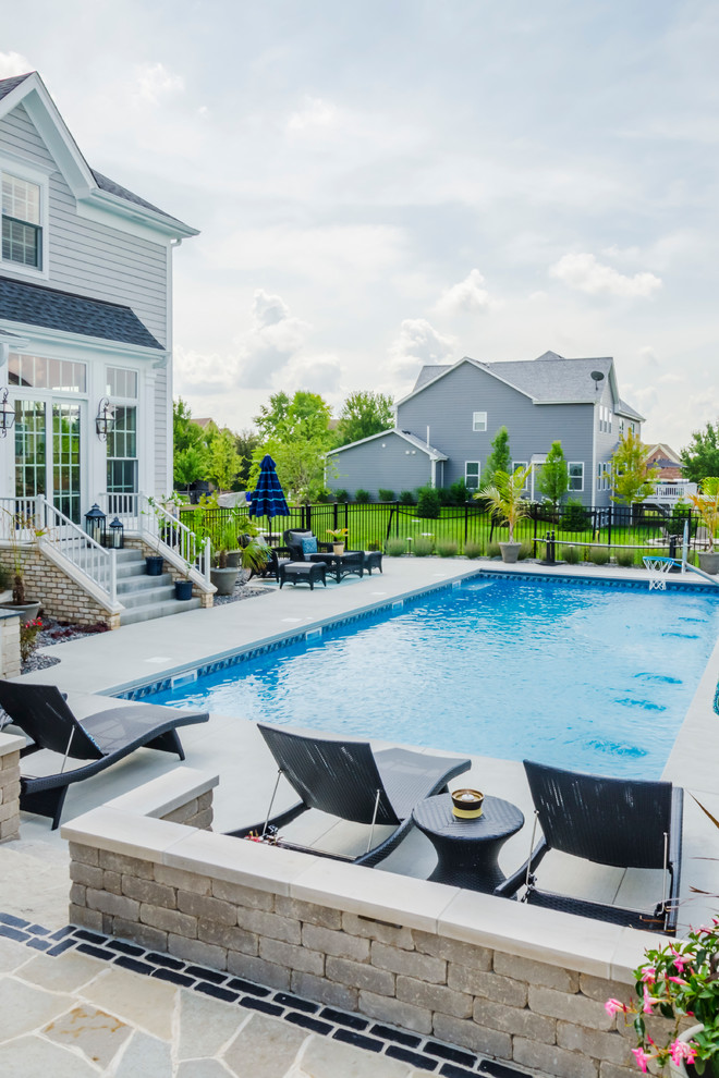Imagen de piscina alargada clásica renovada grande rectangular en patio trasero con adoquines de piedra natural