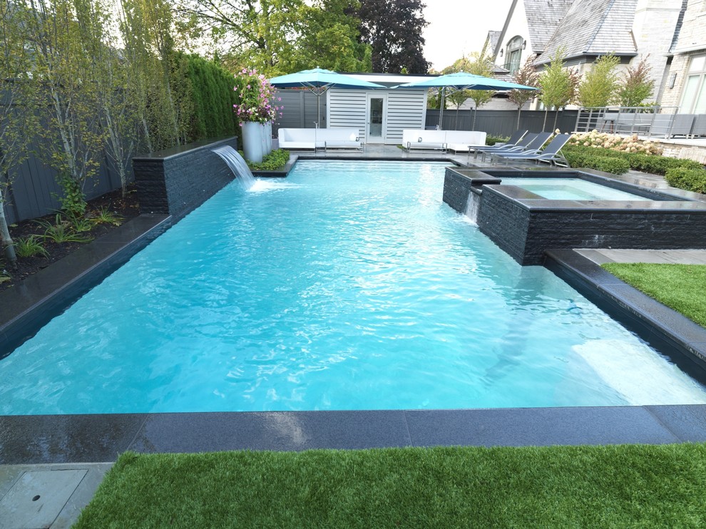 Design ideas for a medium sized contemporary back custom shaped lengths hot tub in Toronto with natural stone paving.