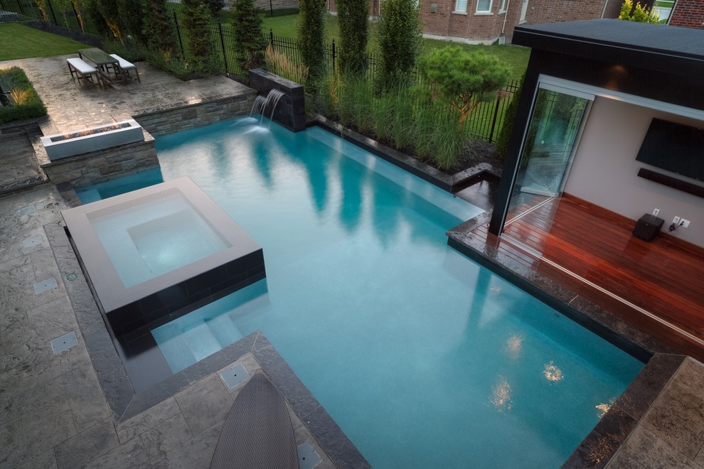 Diseño de casa de la piscina y piscina alargada contemporánea de tamaño medio a medida en patio trasero con adoquines de piedra natural