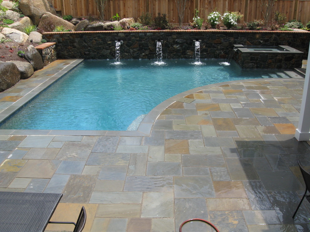 Imagen de piscina con fuente actual pequeña a medida en patio trasero con adoquines de piedra natural