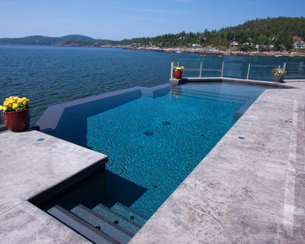 Esempio di una piscina a sfioro infinito contemporanea personalizzata dietro casa con una vasca idromassaggio