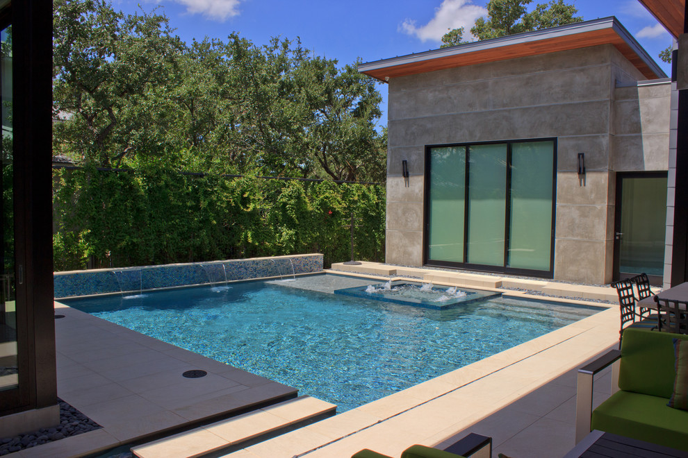 Large contemporary back custom shaped lengths hot tub in Austin with natural stone paving.