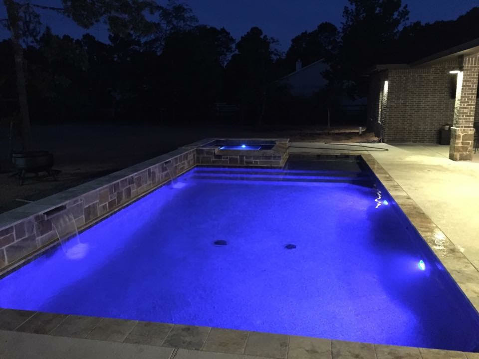 Modelo de piscinas y jacuzzis alargados actuales de tamaño medio rectangulares en patio trasero con losas de hormigón