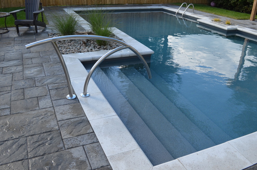 Medium sized contemporary back custom shaped swimming pool in Other with concrete paving.