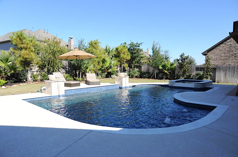 Modelo de piscina con fuente natural actual grande a medida en patio trasero con adoquines de piedra natural