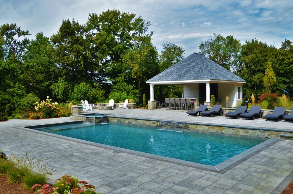 Cette image montre une grande piscine naturelle et arrière traditionnelle sur mesure avec un bain bouillonnant et des pavés en béton.