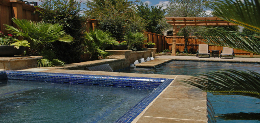 Example of a large island style backyard stone and custom-shaped lap pool fountain design in Dallas