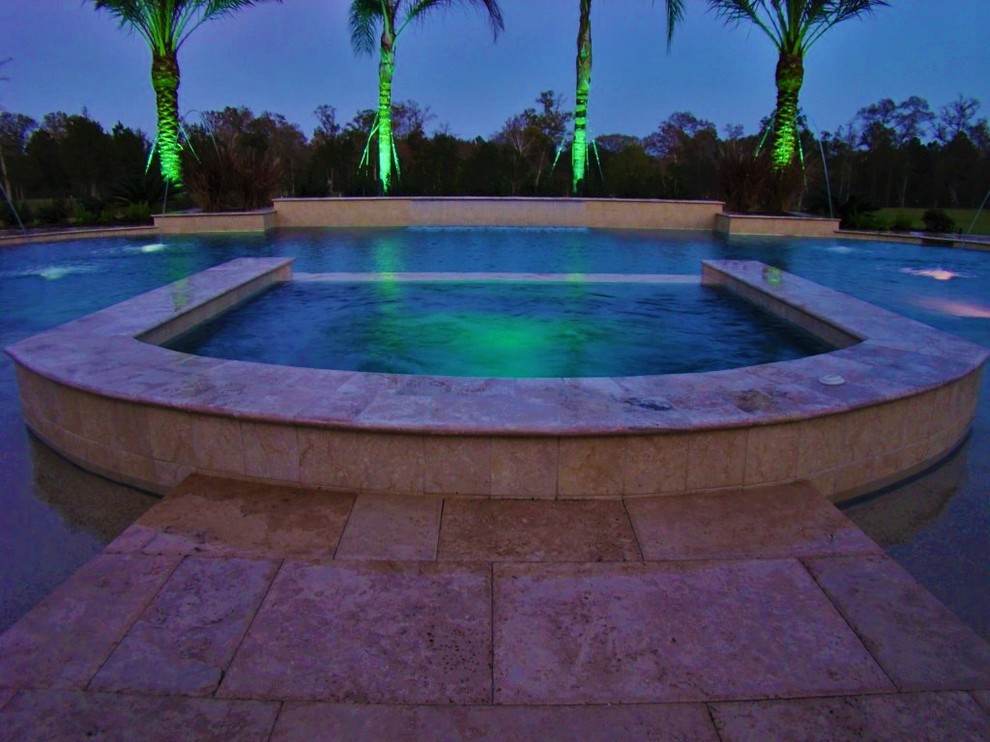 This is an example of a large modern back rectangular swimming pool in Houston with a water feature and stamped concrete.