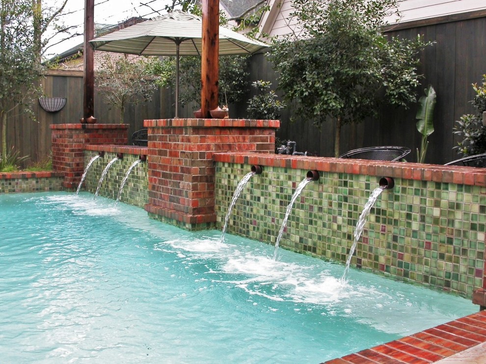 Großer Moderner Pool hinter dem Haus in rechteckiger Form mit Wasserspiel und Stempelbeton in Houston