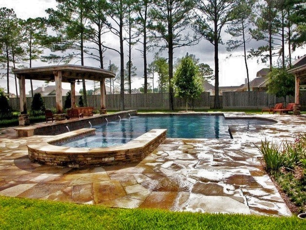 Photo of a large modern back rectangular swimming pool in Houston with a water feature and stamped concrete.