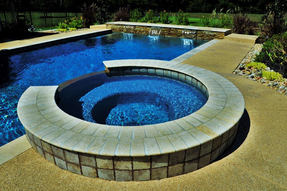 Esempio di una grande piscina moderna rettangolare dietro casa con fontane e cemento stampato