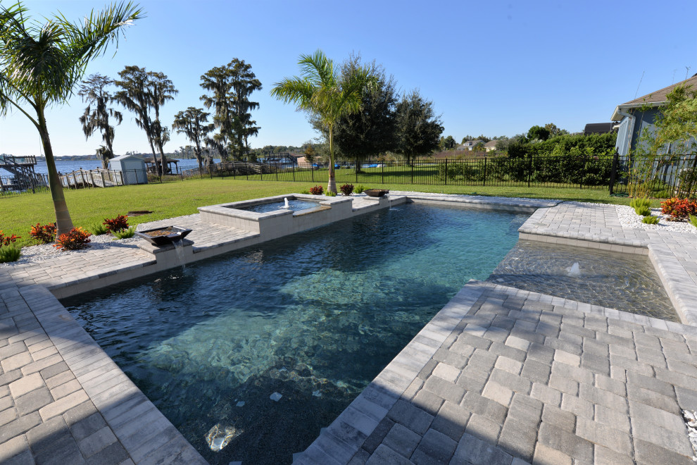 Modelo de piscina clásica grande rectangular en patio trasero con adoquines de ladrillo