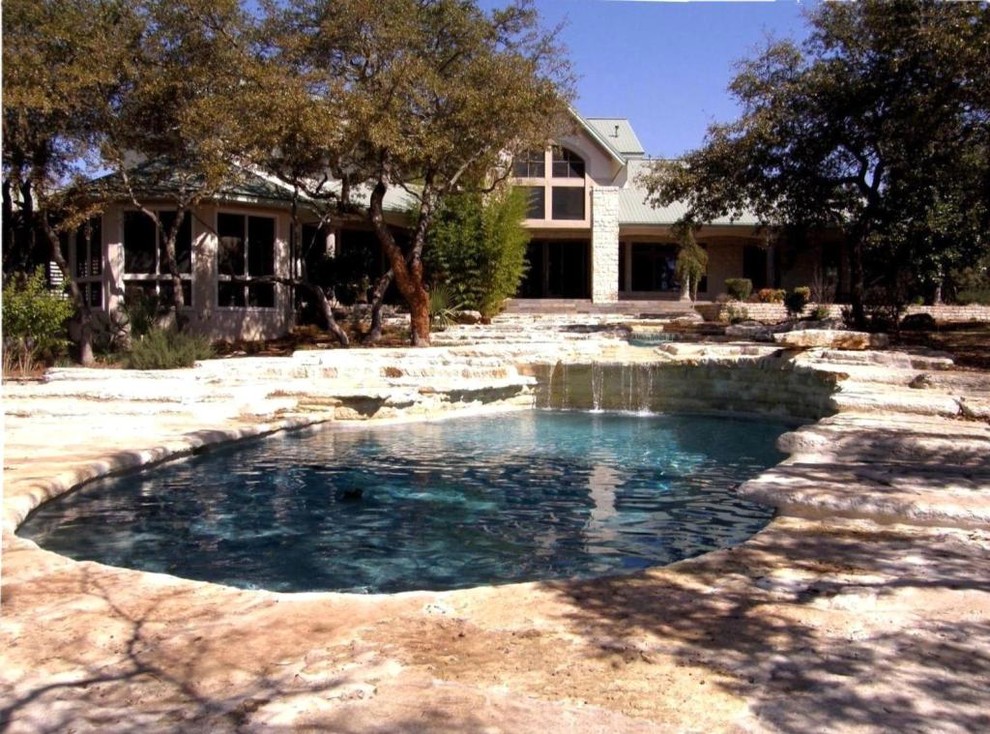 Imagen de piscina con fuente alargada mediterránea grande redondeada en patio trasero con adoquines de piedra natural