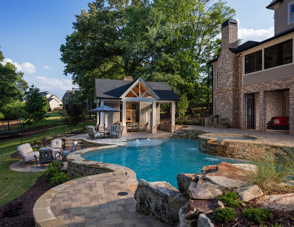 Diseño de casa de la piscina y piscina natural tradicional grande a medida en patio trasero con adoquines de hormigón