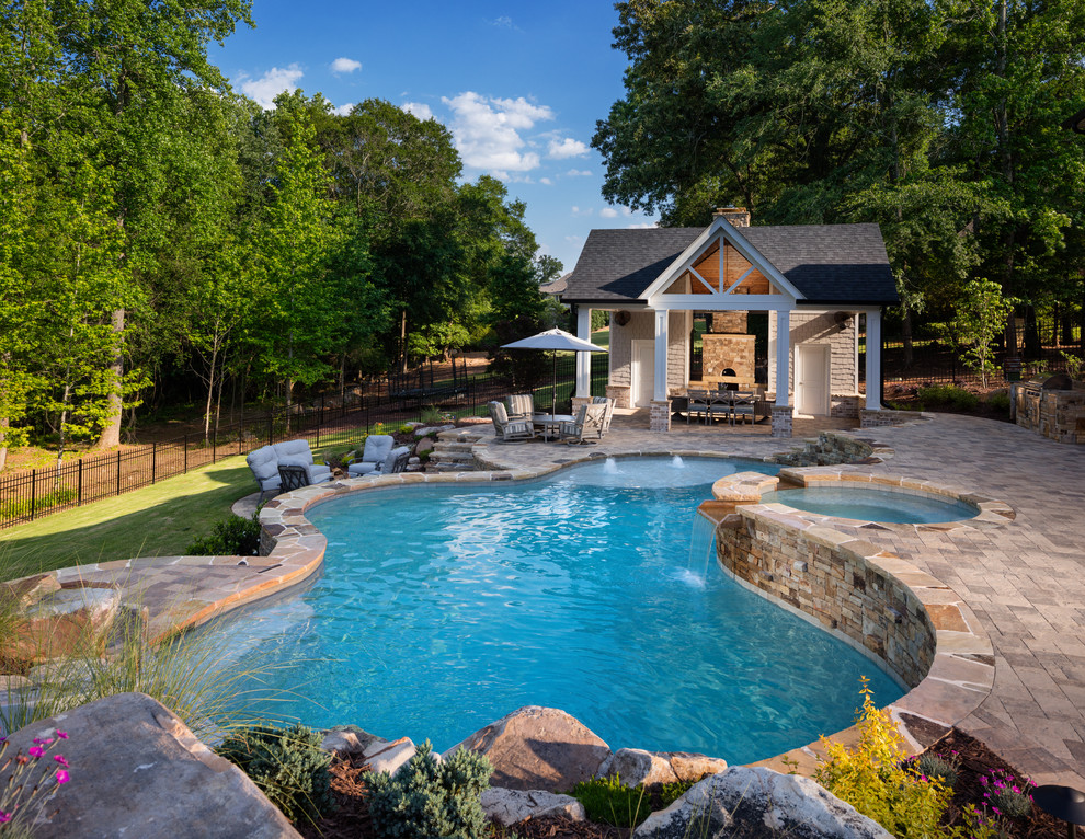 На фото: большой естественный бассейн произвольной формы на заднем дворе в классическом стиле с домиком у бассейна и мощением тротуарной плиткой с