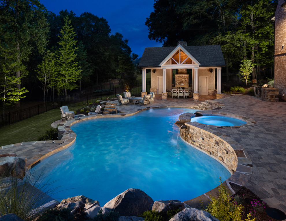 Ejemplo de casa de la piscina y piscina natural clásica grande a medida en patio trasero con adoquines de hormigón