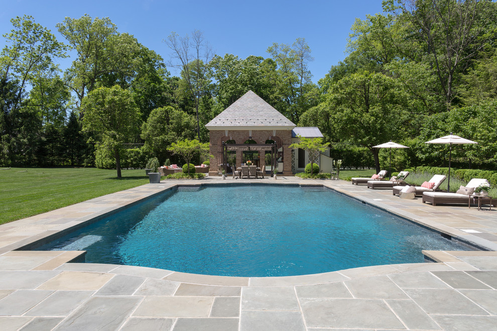 Diseño de casa de la piscina y piscina alargada clásica grande rectangular en patio trasero con suelo de baldosas