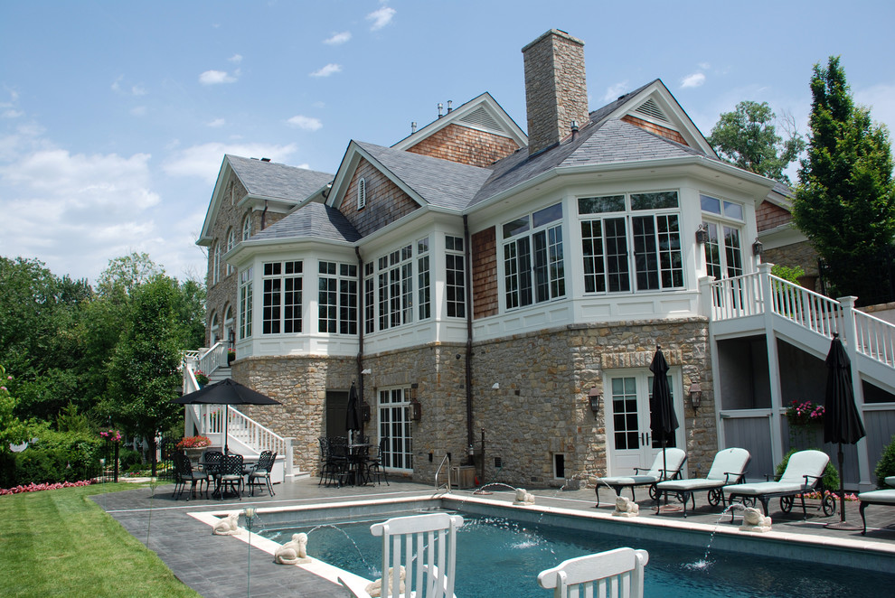 Modelo de piscina con fuente alargada clásica grande rectangular en patio trasero con adoquines de piedra natural