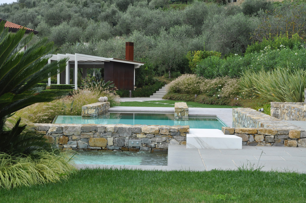Immagine di una grande piscina fuori terra contemporanea rettangolare dietro casa con fontane e pavimentazioni in pietra naturale